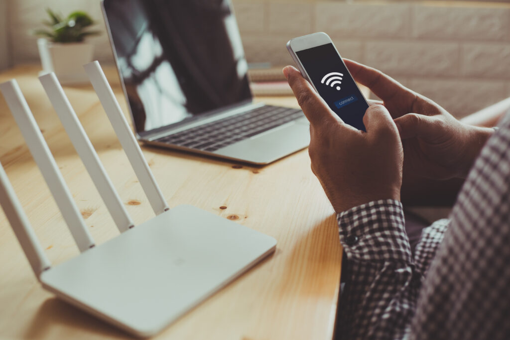 A technician configuring a Wi-Fi router using a smartphone, representing smart home internet setup and installation.
