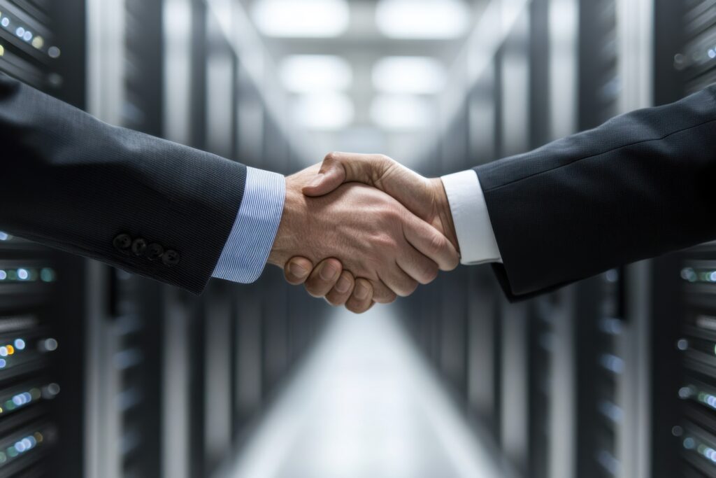 Two professionals shaking hands in a secure IT server room, symbolizing managed network partnership and business agreement