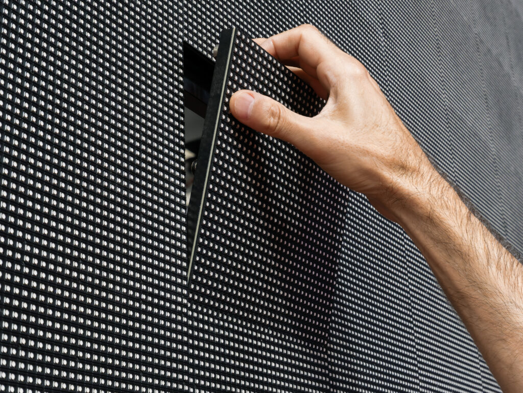 Technician hand removing LED video wall module for maintenance and repair
